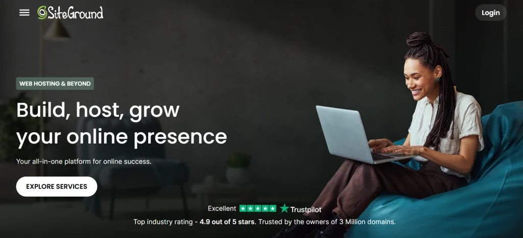 Smiling woman with braided hair working on laptop in relaxed teal beanbag setting for SiteGround web hosting